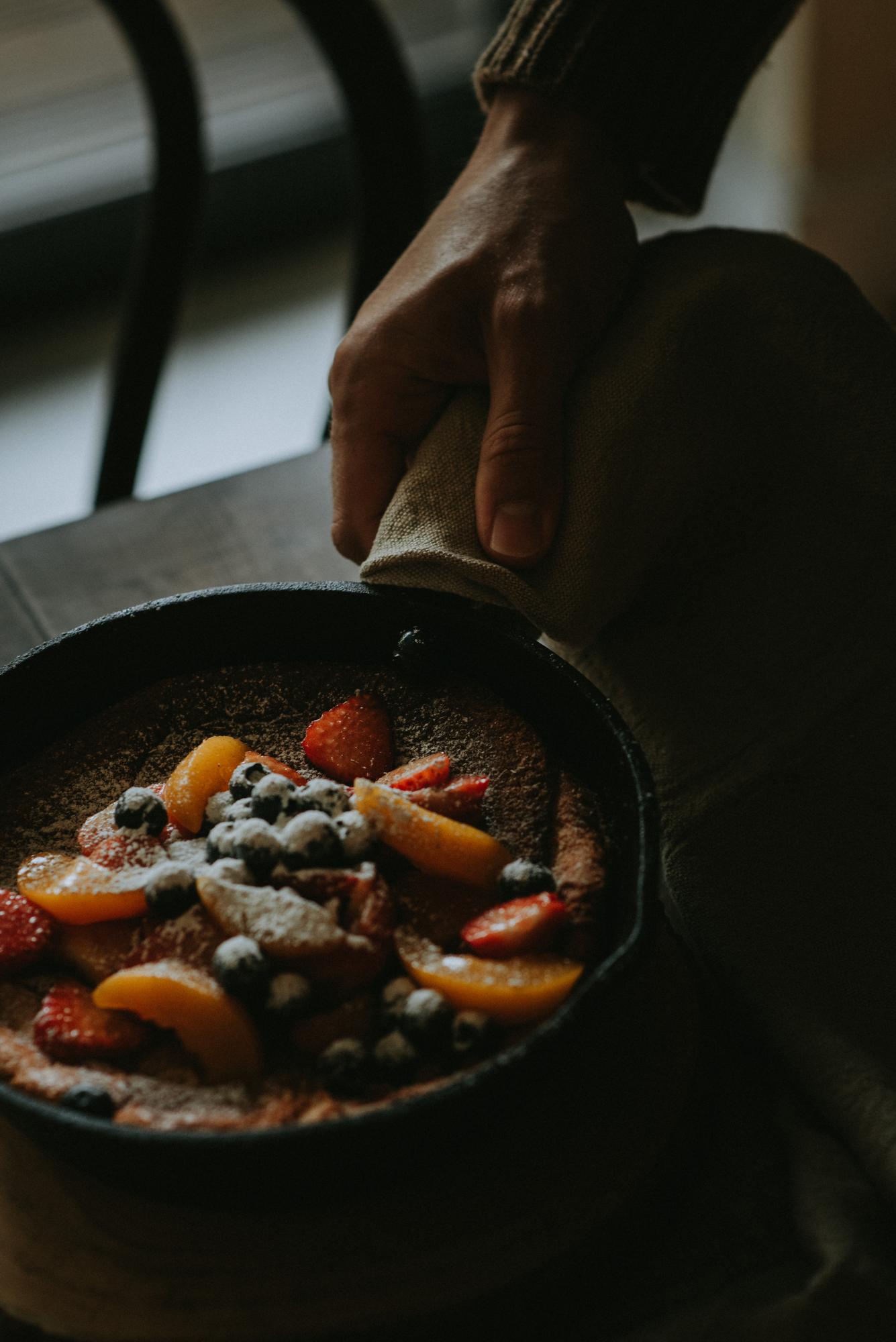 A chef plating a simple rustic dish on a wooden table